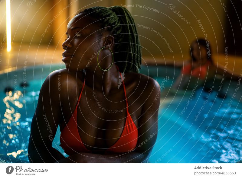 Black women relaxing in hot tub friend spa water wellbeing procedure skin care body care chill trendy feminine wellness female african american bikini swimsuit