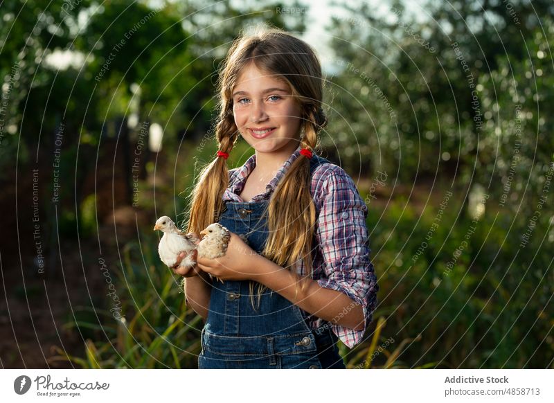 Optimistic girl with chicks on farm farmer countryside smile summer animal positive portrait daytime kid casual carry cheerful happy rural cute adorable nature