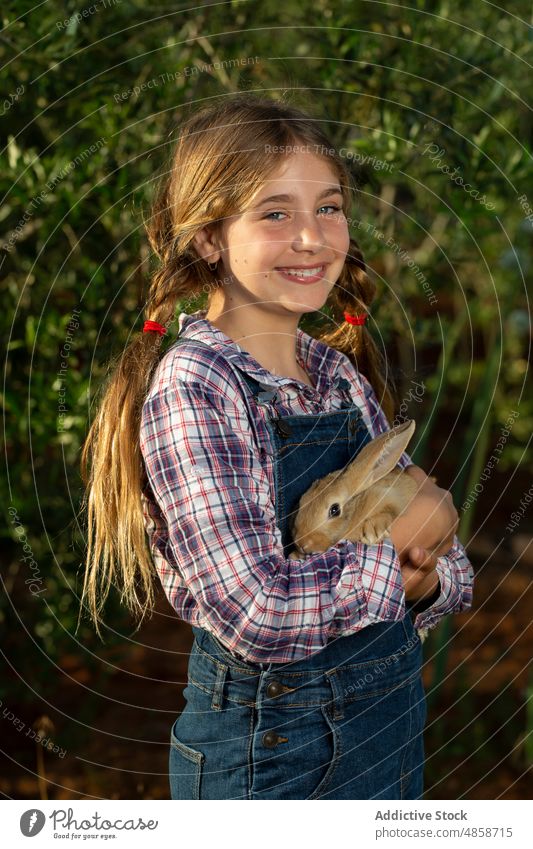 Little farmer with rabbit in garden girl countryside hug smile summer animal portrait positive daytime kid casual cheerful happy bunny rural little cute