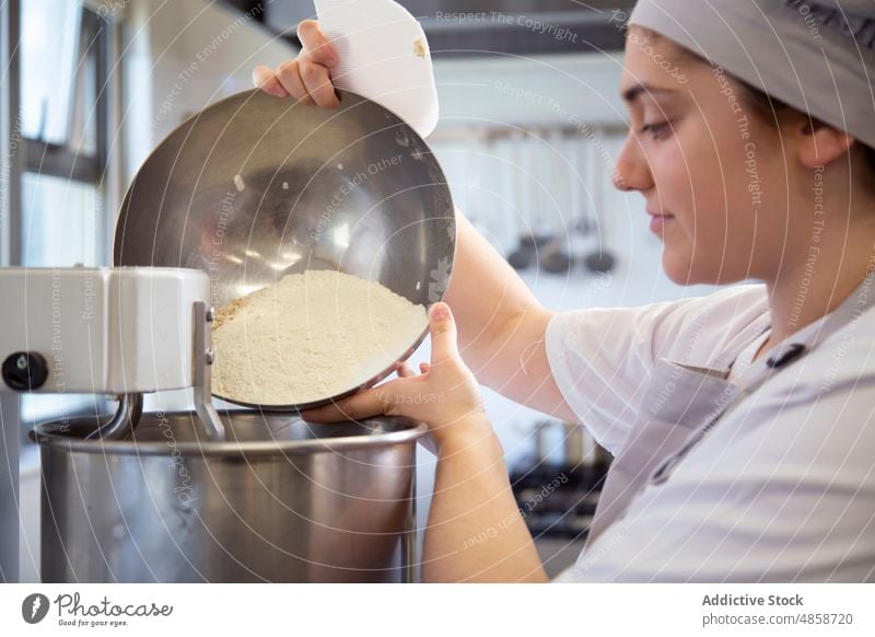 Woman pouring flour into dough mixer woman baker machine equipment culinary bakery recipe appliance kitchen work bowl industry job product electric automatic
