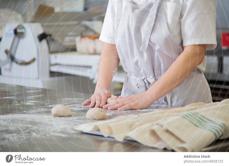 Anonymous baker preparing dough on table woman culinary raw bakery kitchen work recipe industry job serious flour process equipment bakehouse uncooked ball