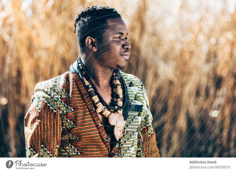 African man in beaded jacket near field tradition outfit style fashion ornament necklace authentic male black ethnic african accessory grass dry nature local
