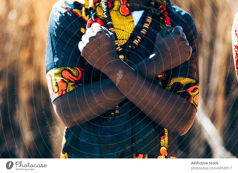 Crop African man crossing arms with clenched fists arms crossed clench fist gesture power field tradition style culture countryside fashion daytime male black