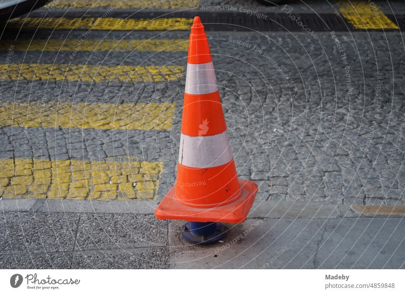 Traffic cone or pylon mounted on a foreman at a yellow crosswalk on old cobblestones in the old town of Konak in the light of the setting sun at Konak Square in ancient Smyrna and present Izmir on the Aegean Sea in Turkey