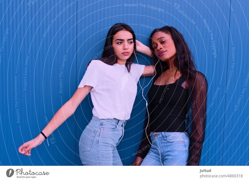 Two friends embrace each other in front of a blue wall. Girl Ethnicity spain Young Woman Twenties Trendy BuildingExterior Girlfriend Friendship Female Friends