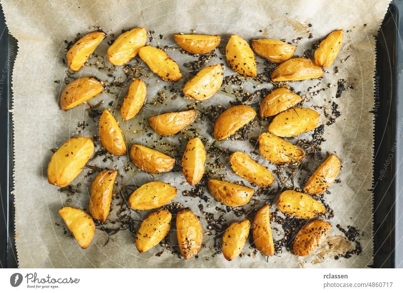 Baked potato wedges on baking tray -  homemade organic vegetable vegan vegetarian potato wedges snack food meal. fried cooked spicy top baking paper view