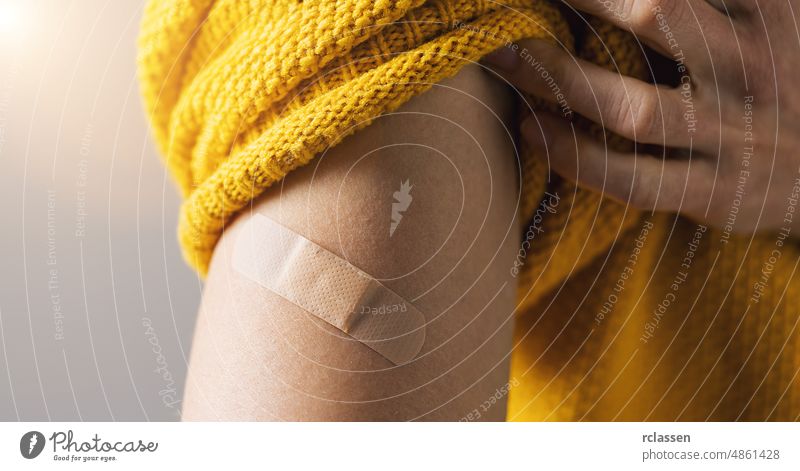 vaccine for corona COVID-19 and SARS cov. Woman holding up her sweater sleeve and showing her arm with Adhesive bandage Plaster after receiving vaccination injection, banner size