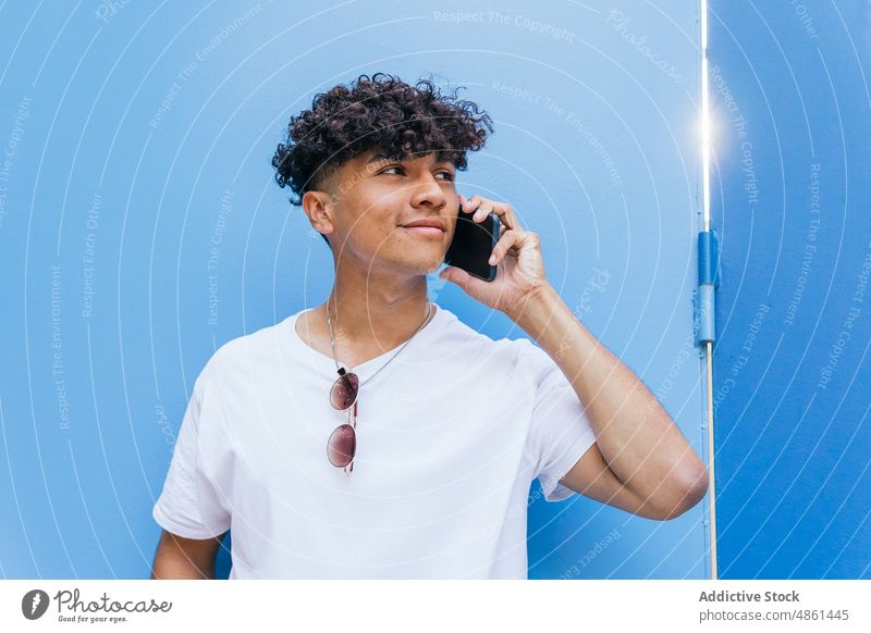 Young ethnic man talking on the phone on the street smartphone mobile lifestyle positive online internet social media device modern male afro free time
