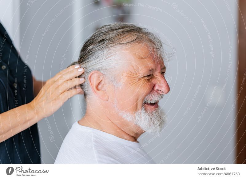 Faceless woman doing hairstyle to senior man hairdo help elderly prepare room gray hair husband smile wife cheerful relationship partner positive content