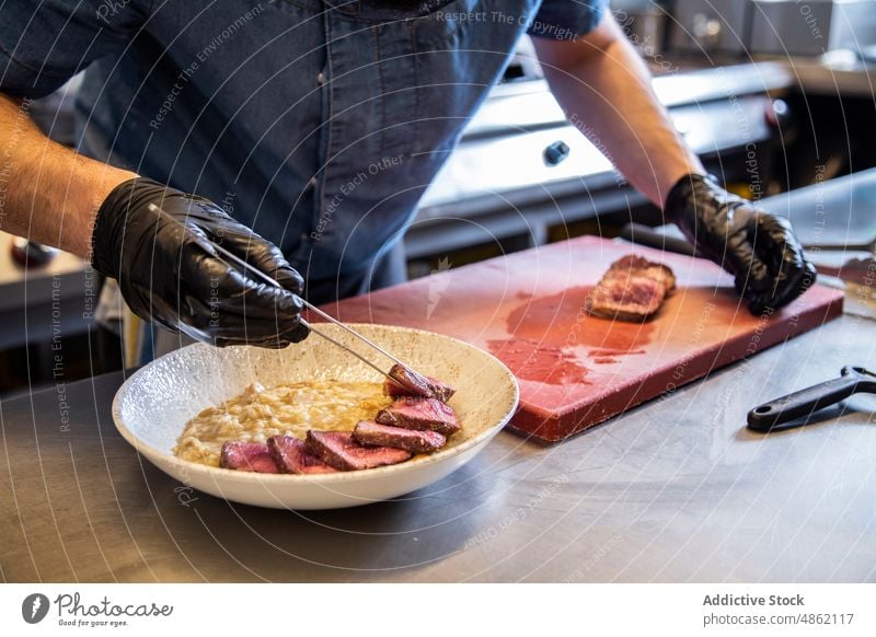 Chef Placing Steak Slices In Bowl On Counter In Restaurant Kitchen Dish Lunch Meat Rice Grill Cutting Board Tongs Glove Holding Cooked Food Commercial Cooking