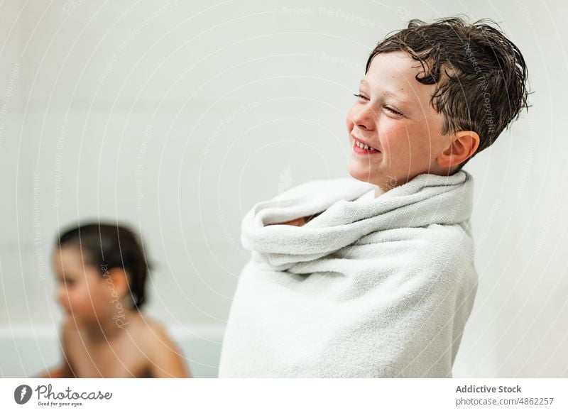 Positive boy wrapped in white towel after bathing smile child bathtub hygiene procedure bathroom portrait kid toothy smile happy positive cheerful joy daily