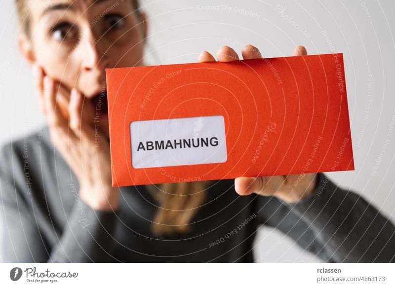 Abmahnung (German for: final notice) Hand Holding and showing a Receiving a Final Notice Envelope concept of lawyer or business envelope shocked fear debt red