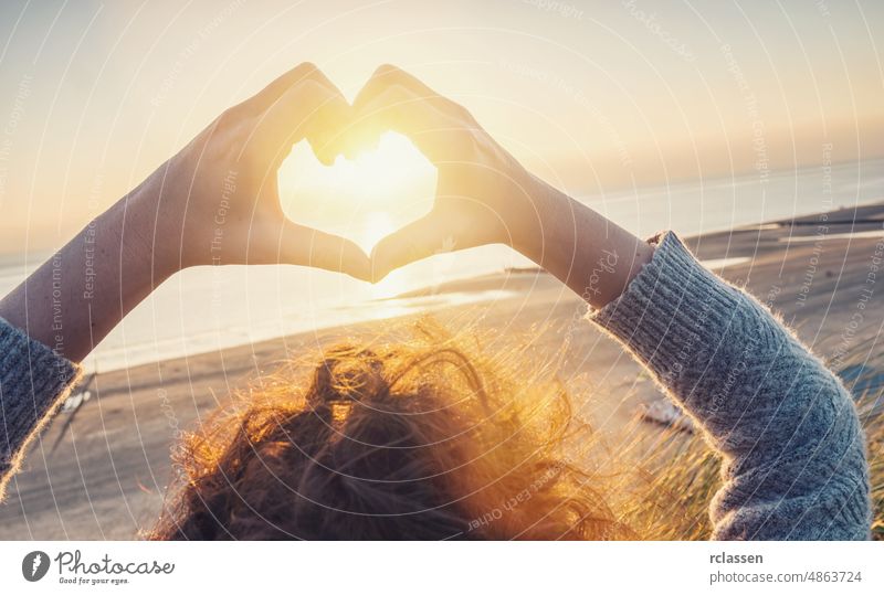 Woman hands in Heart symbol shaped with sunset light on the beach, Lifestyle and Feelings concept image woman heart lifestyle travel love harmony curls sunlight