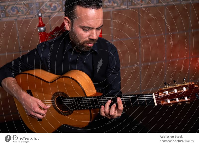 Bearded man playing song on guitar guitarist musician instrument hobby acoustic practice talent male skill perform melody beard player sound chord unshaven wall
