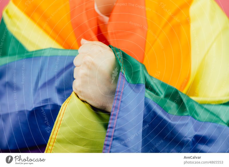 Close up hand over flag. Woman smiling happily to camera while holding a LGBTIQ flag around her showing pride. Lesbian woman, pride and fighting for her rights. Love is love concept.
