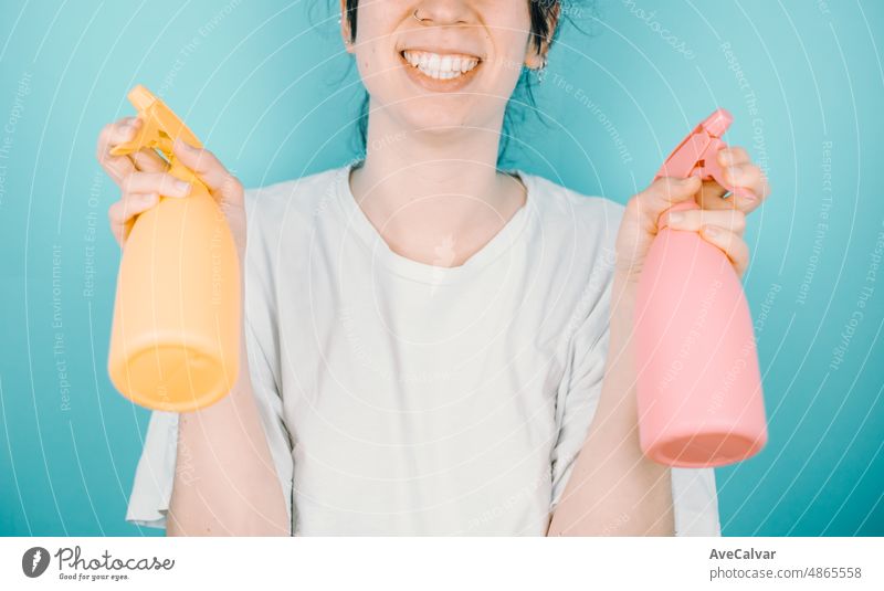 Young woman smiling happily to camera while holding a pair of water sprayer to refresh during summer. Holidays outdoors with copy space.Color background image