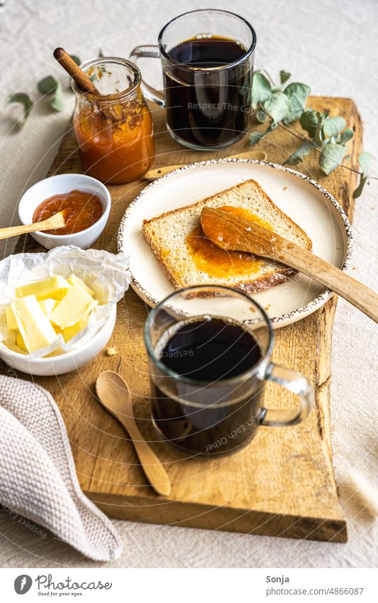 Two glasses of coffee, a slice of bread, butter and apricot jam on a wooden serving tray Breakfast Coffee Slice of bread Butter Jam Apricot cute Espresso Food