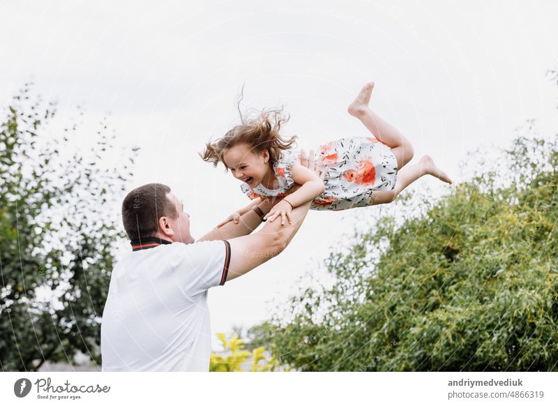 Young father throwing his baby daughter high in the sky in the park in summer day. father's day happy childhood joy kid little dad people fun family outdoor