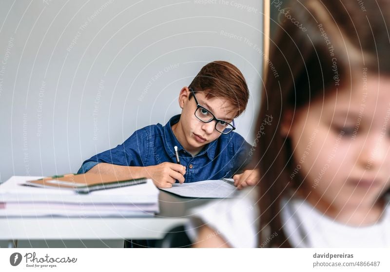 Teen writing in notebook at school teen student looking camera classroom smart studious education people young boy girl female two person child kid serious