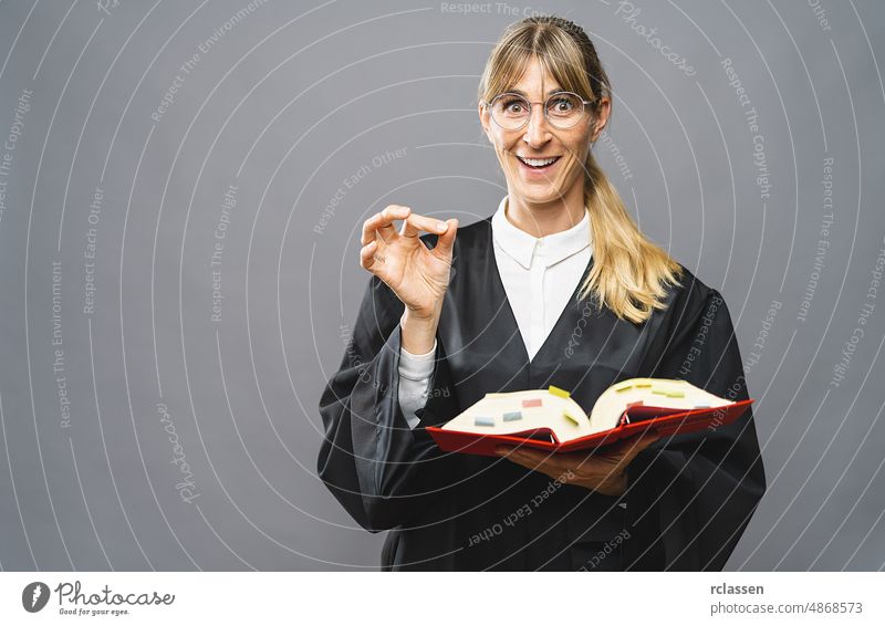 Female Lawyer with civil law code book shows correctly sign with hand in a court room. Law and justice concept image german lawyer paragraph lady justice gray