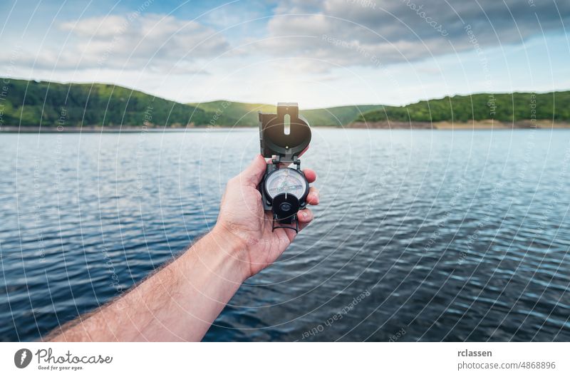 Traveler man searching direction with a compass on a coastline near a lake in the mountains. Point of view shot. holding pov orientation hand people lifestyle