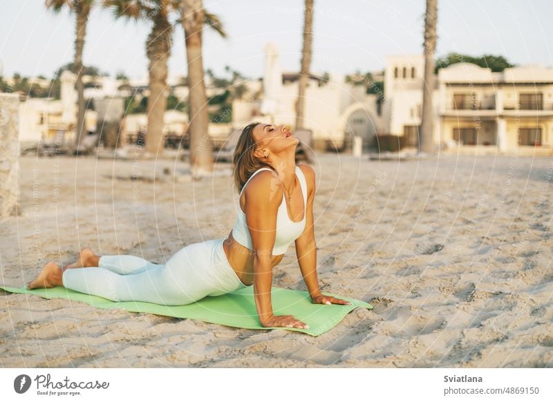 A young girl practices yoga on the beach. Sports, fitness, yoga. The concept of care and healthy lifestyle woman beautiful summer ocean sunset seaside holiday