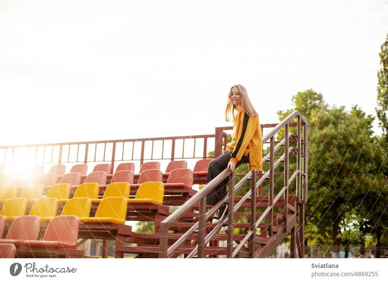 A teenage girl has fun and slides down the railing at the stadium stairs ride beautiful railings cool play teenager staircase childhood lifestyle street fashion