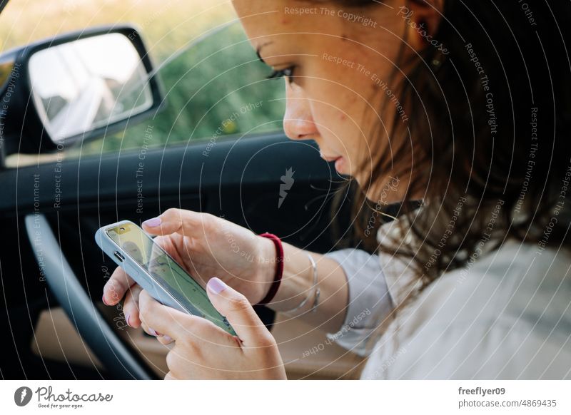 Young woman looking at her phone smartphone car maps screen mobile using closeup hand lifestyle taxi distracted contraption adult glow text message blank city