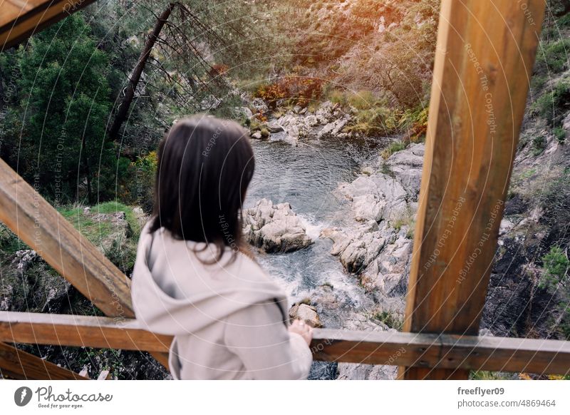 Woman contemplating a river from a wood bridge woman pond forest portrait young caucasian tourist walking mountain hiking posing nature copy space galicia