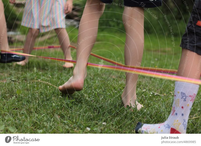 Children playing bouncy rubber together outside on the lawn rubber twist Children's game children Kindergarten Hop in common Infancy Barefoot socks Summer