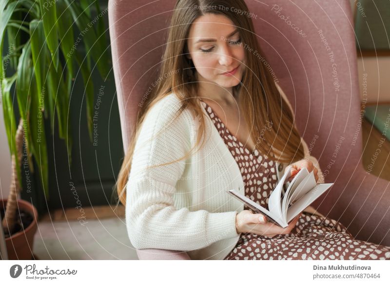 person reading a book at the library. Young woman reading books, studying at the university library, or coworking space, office or at home. Back to school concept.
