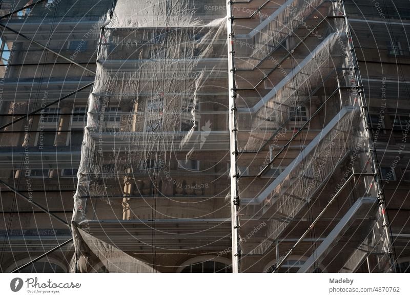 Preservation of old building fabric by renovation with scaffolding and protective net in sunshine on an old building in the old town of Münster in Westphalia in the Münsterland region of Germany