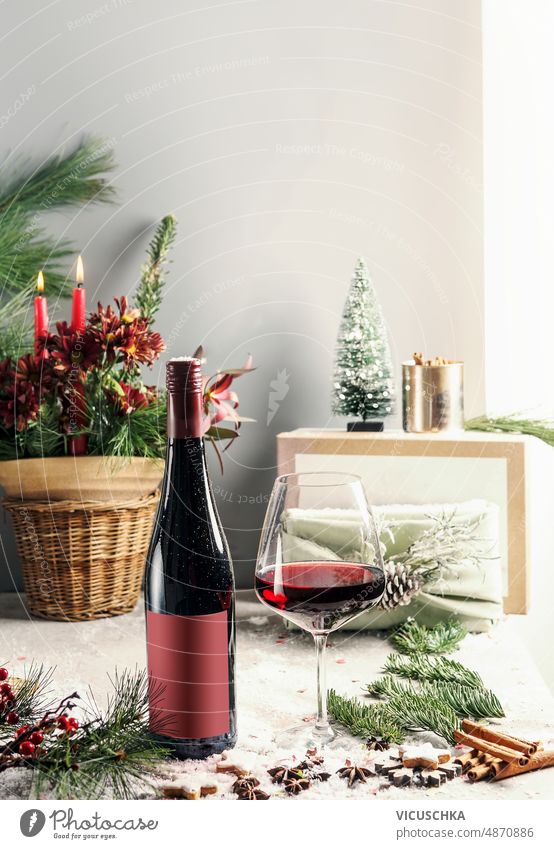 Red wine bottle with wineglass and fir green at table with Christmas decoration and winter spices still life red wine christmas decoration wall background