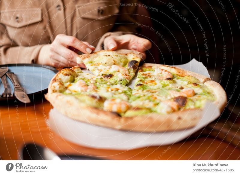 Eating pizza at pizzeria. Pizza closeup in the carton box - pizza delivery and eating at home. Fast food habits. Pizza order from app and delivered at home. Woman eating pizza at restaurant, taking a slice.