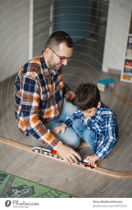 Father and son playing with toy railway and train. happy family spending time together. Dad and son. Parenthood and Father's Day. childhood design cheerful