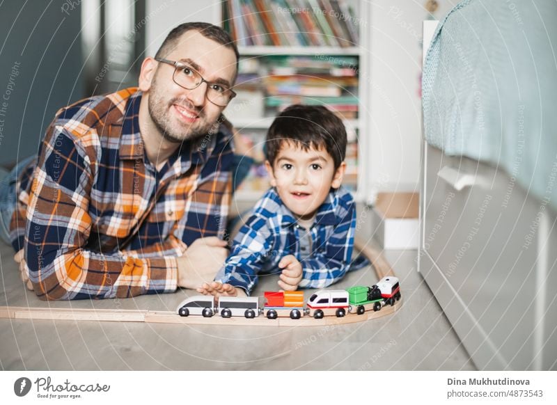 Father and son playing with toy railway and train. happy family spending time together. Dad and son. Parenthood and Father's Day. childhood design cheerful