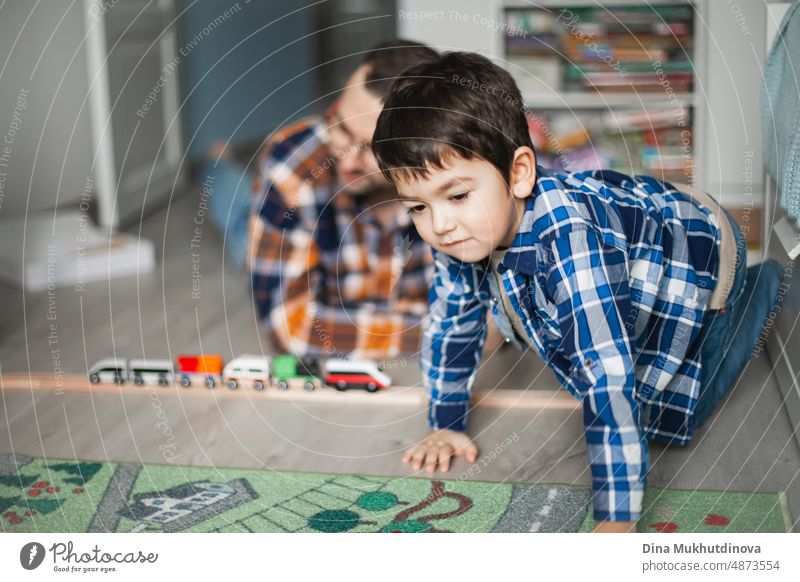 Father and son playing with toy railway and train. happy family spending time together. Dad and son. childhood design cheerful internet poster caucasian