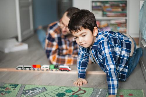 Father and son playing with toy railway and train. happy family spending time together. Dad and son. childhood design cheerful internet poster caucasian