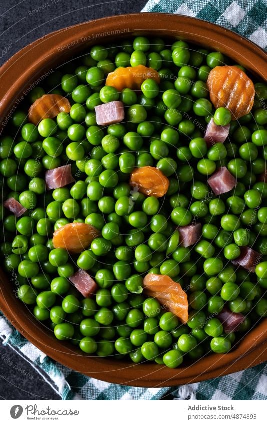 Green peas with serrano ham and carrot on table green vegetable healthy mix dinner food lunch spanish cooked colorful bright bowl organic natural ingredient