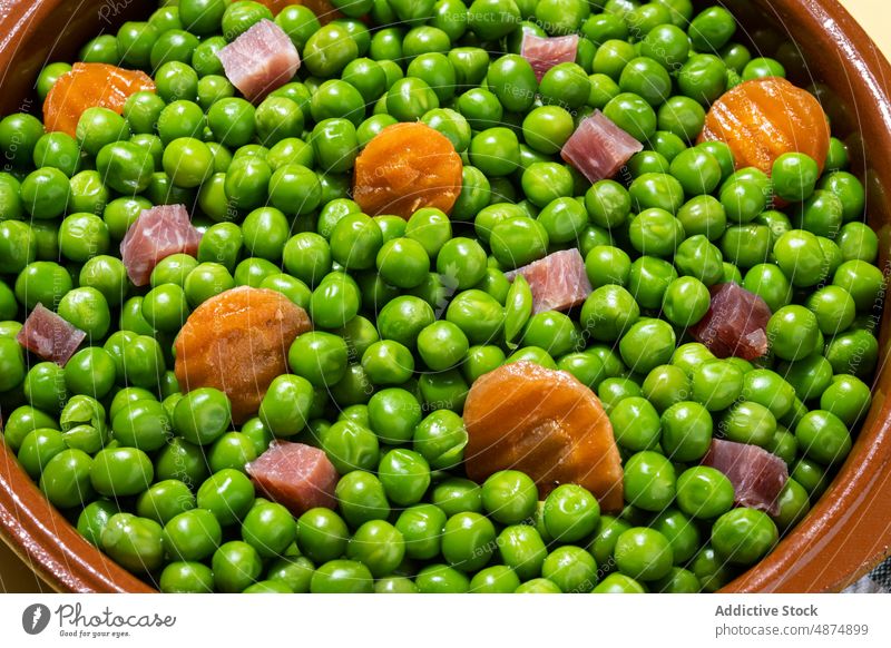 Green peas with serrano ham and carrot on table green vegetable healthy mix dinner food lunch spanish cooked colorful bright bowl organic natural ingredient
