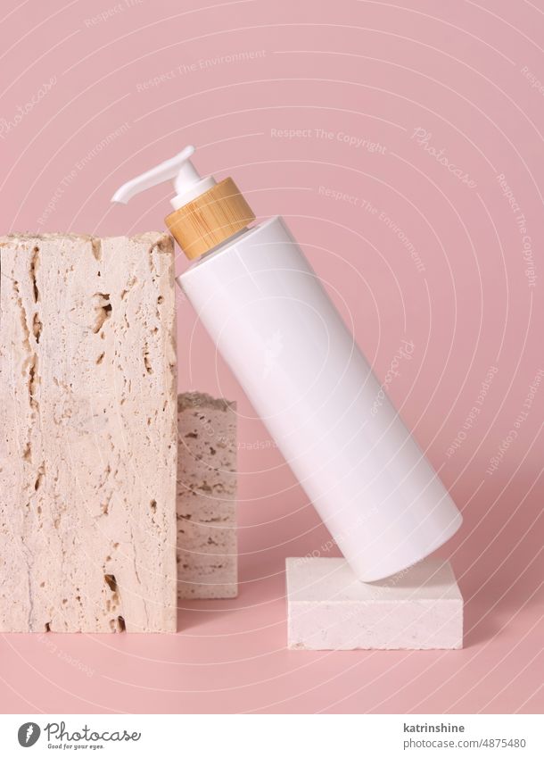 White one pump bottle lies on stone on light pink close up, Mockup mockup white lotion cleanser negative space copy space Brand package plastic natural
