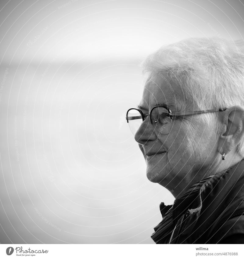 Good mood senior woman on vacation in text free space Senior citizen White-haired Short-haired cheerful Smiling portrait Eyeglasses earring B/W Pensioner