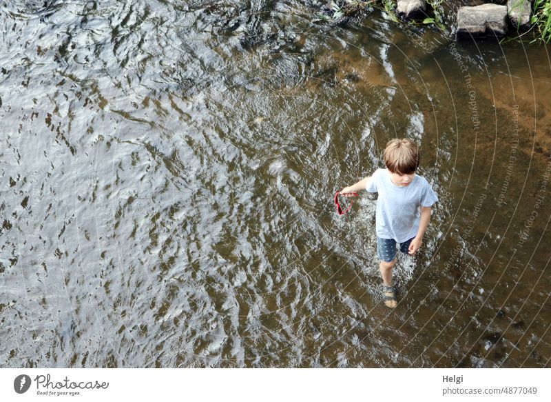Boy strolls casually with sunglasses in hand on the bank of the Fulda through the water Human being Child Boy (child) 8 years Water River River bank