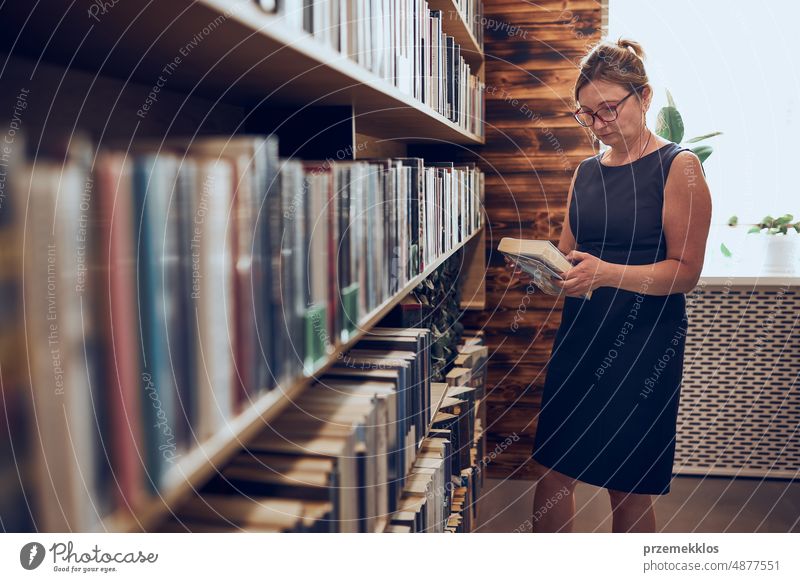 Woman reading book in public library. Searching for literature for reading and learning. Selecting books. Benefits of everyday reading. Books on shelves in bookstore