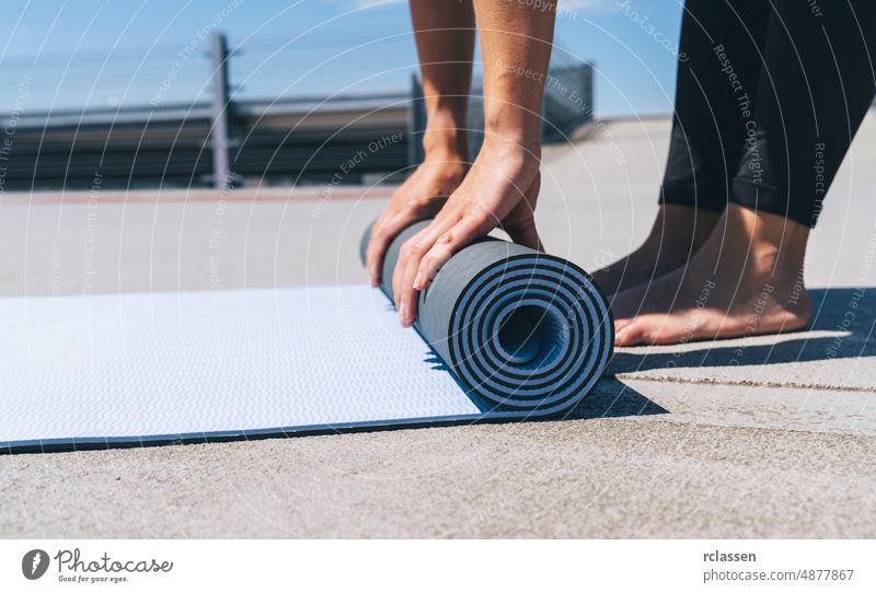 young woman folding blue yoga or fitness mat after working out. keep fit concepts image. copyspace for your text. pilates power european people beautiful
