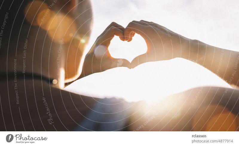 Female hands in the form of heart against the sky pass sun beams. Hands in shape of love heart summer rear view concept healthy sign image valentine day people