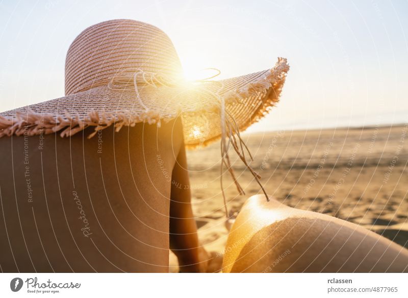 tanning woman wearing sun hat over her legs on the beach at sunset beauty sand summer casual top girl view skin background barefoot shell above fashion body
