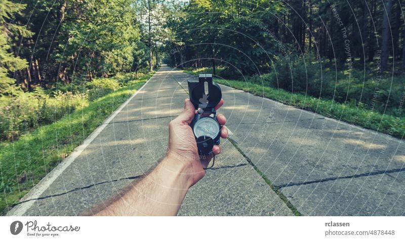 Travel Concept man hand hold Compass on the road in the outback. Point of view shot compass holding pov orientation people lifestyle orienteering point