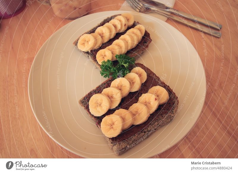 Whole grain bread loaf with chocolate spread topped with banana slices for a healthy vegan breakfast and a healthy sustainable lifestyle vegan food