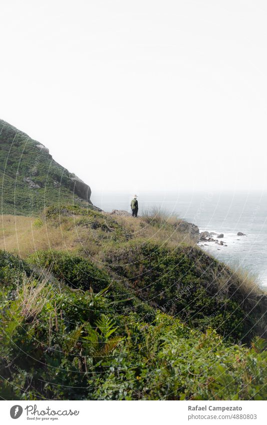 man wearing hat on cliff edge looking at horizon vertical photo Photography Man Hat Green Cliff thinking real people Landscape White Gray Beach Seasons Fine Art
